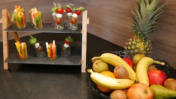 Eine Obstauslage mit verschiedenen Früchten, darunter Bananen, Äpfel und Orangen auf einem Tisch.
