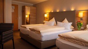 Habitación de hotel con dos camas, una silla y un florero con flores.