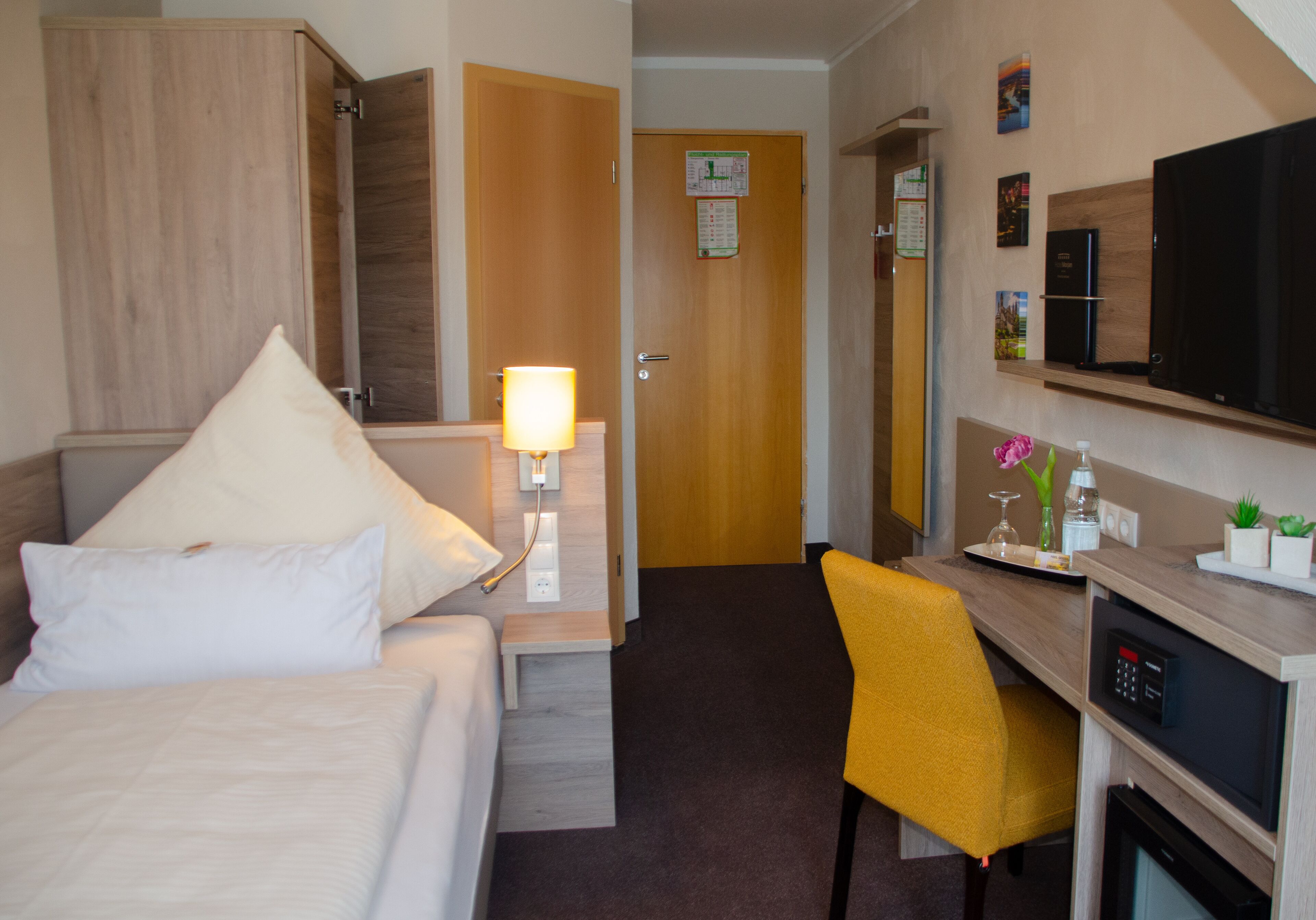 Una habitación de hotel con cama, escritorio, silla, televisión y microondas.