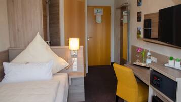 Una habitación de hotel con cama, escritorio, silla, televisión y microondas.