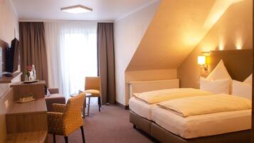 A hotel room with a bed, a desk, a chair, and a TV.