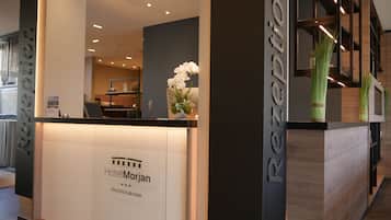 Un mostrador de recepción de diseño moderno, con el logotipo y el nombre del hotel, y una planta en maceta.