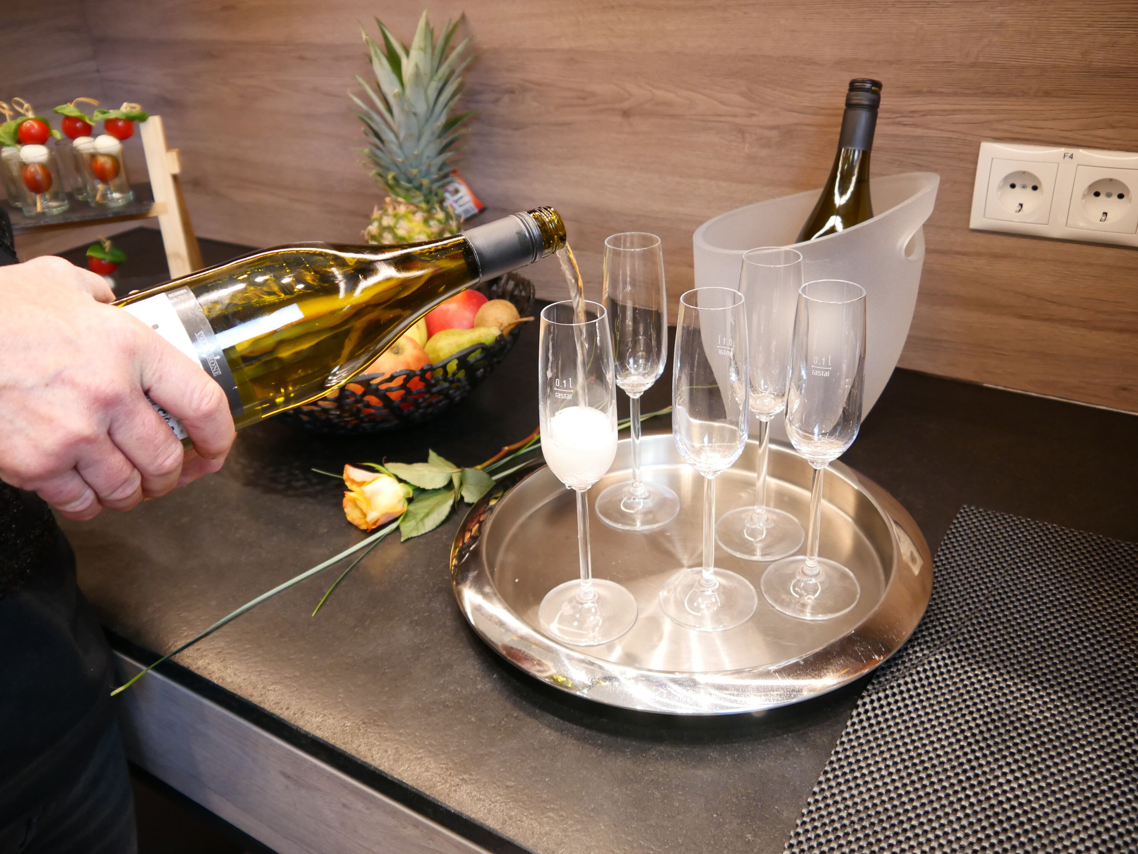 A person pouring wine into glasses on a tray.