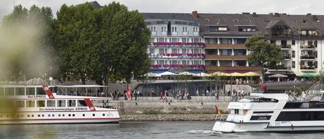 Hotel aan de rivier met meerdere balkons, terras buiten en uitzicht op de rivier.