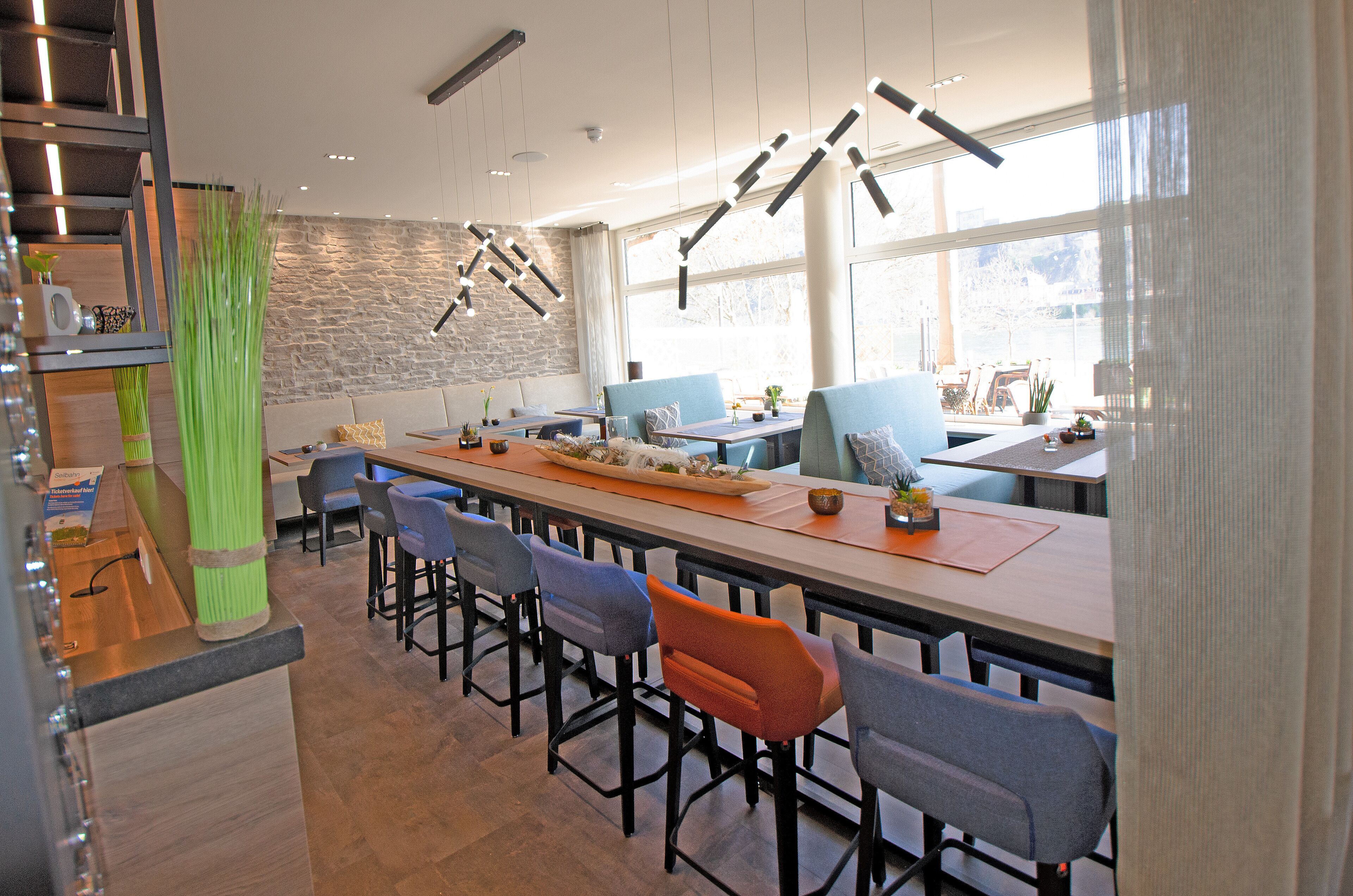 A modern restaurant with a long counter, multiple seating options, and a stone accent wall.