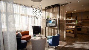 Una sala de estar moderna con un sofá, sillones, una mesa de centro y un televisor montado en la pared.