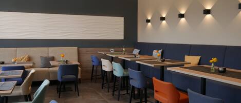 Un restaurante moderno con cabinas, asientos en la barra y decoración contemporánea.