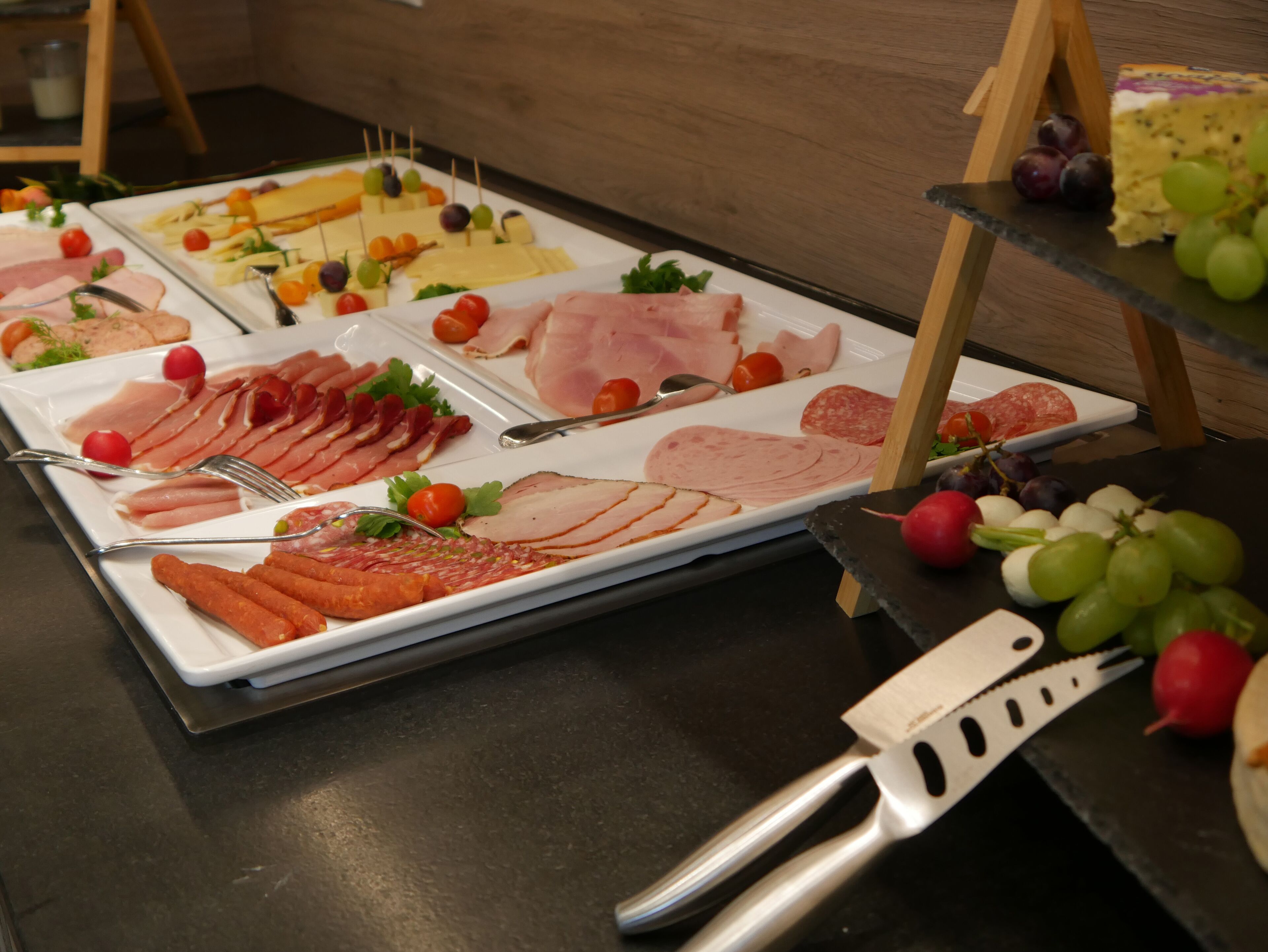 A buffet table with various meats, cheeses, and fruits.