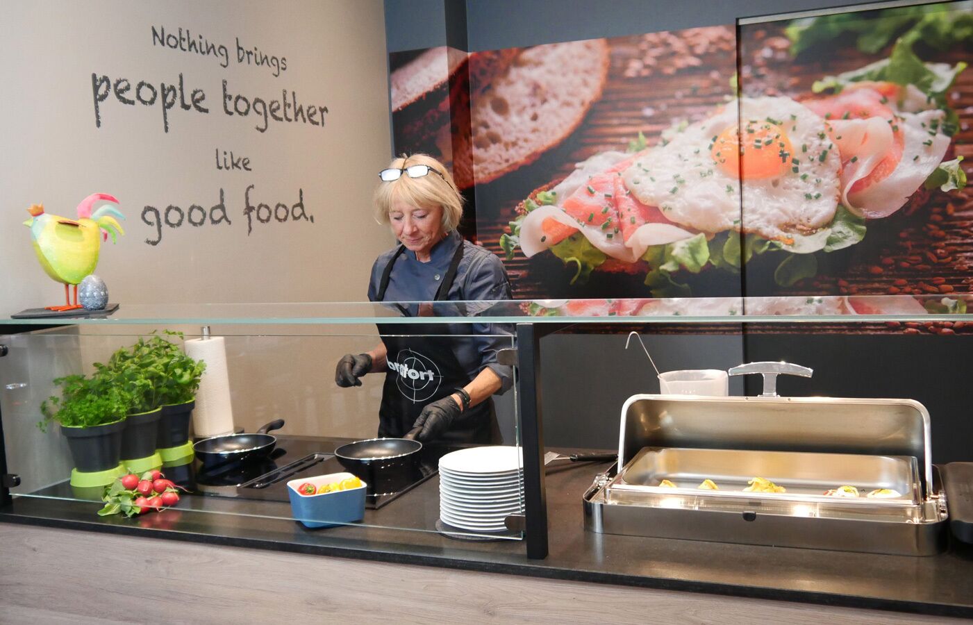 A buffet setup with a chef preparing food, a sign with a message, and various food items displayed.