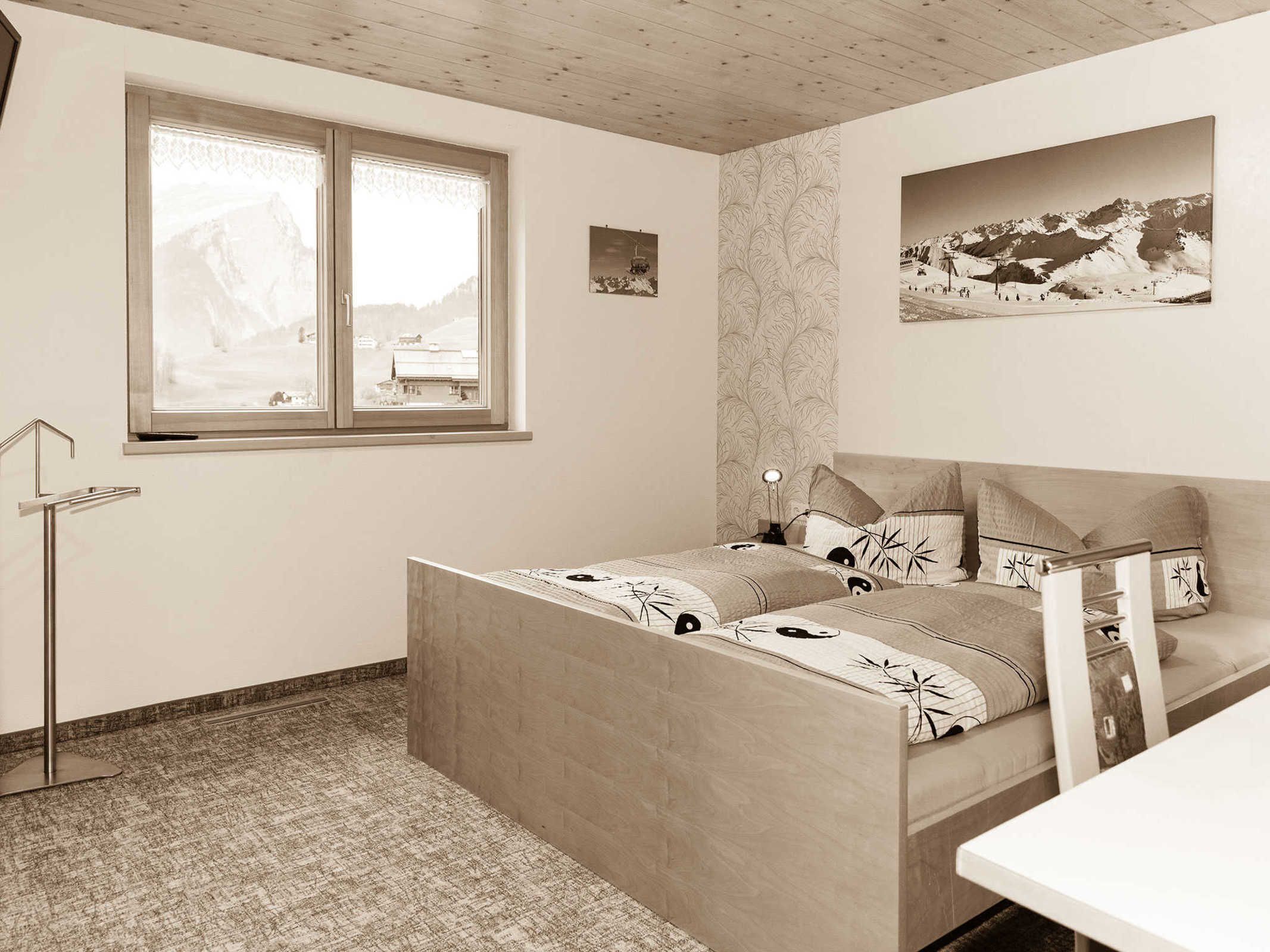 Una camera da letto con un letto, una finestra vista montagne, un comodino e una sedia.