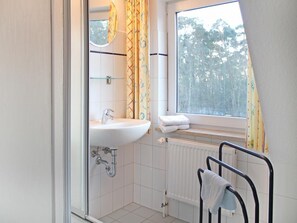 Une salle de bain avec un lavabo blanc, un miroir et un porte-serviettes.