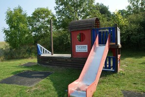 Ein Spielplatz mit Rutsche und Spielhäuschen.