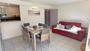 A compact living space with a dining area, a red sofa, and a kitchen area. - Apartment for 4/6 people - Swimming pool - Air conditioning - WiFi - Near center - Sainte Maxime... (STE MAXIME)