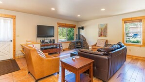 A living room with a fireplace, leather sofas, a TV, and a wooden coffee table. - Heart of Truckee: Modern Truckee Escape with A/C, Kids' Room & Walkable Location (Truckee)