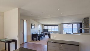 A modern kitchen with a dining area, large windows, and a stone fireplace. - Lake and Mountain Ridge - Queenstown Apartment (Queenstown)