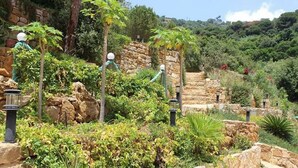 A garden with stone walls, various plants, and a staircase leading up a hill. - Pinewood Hotel (Jeita)