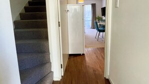 A hallway with a wooden floor leading to a dining area with a table and chairs.