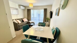 A compact living space with a dining area, a sofa, a small table, and a television.