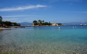 Paisaje costero con aguas cristalinas, costa rocosa y barcos.