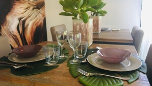 Une table à manger dressée avec de la verrerie, des assiettes et une plante.