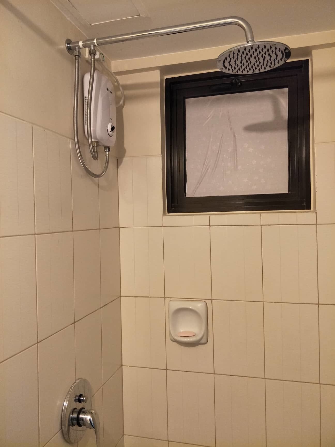 Ein Duschbereich mit Handbrause, integriertem Fenster und einer kleinen Seifenschale.