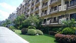 Un hôtel à plusieurs étages doté de balcons, d’un parking et d’un aménagement paysager bien entretenu.