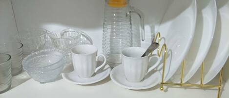 Une étagère de cuisine contenant divers articles en verre, notamment des tasses, des bols et une carafe à eau.