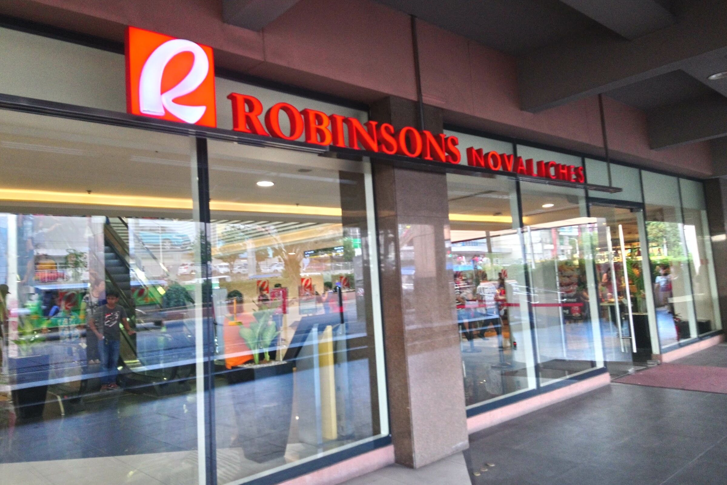 Une devanture de magasin avec une grande enseigne en forme de « R » et le nom « Robinsons Novelties ».
