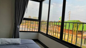 A hotel room with a large window, a bed, and a curtain. - Nitta Ville (Hang Chat)