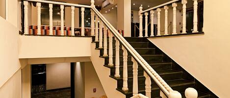 Una imponente escalera con barandillas blancas y peldaños negros que conduce a un piso superior.