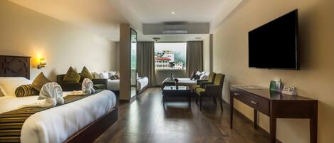 A hotel room with a bed, a desk, a chair, a television, and a view of a building outside.