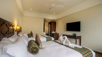 A hotel room with a large bed, a flat-screen TV, a desk, and a ceiling fan.