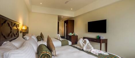 A hotel room with a large bed, a flat-screen TV, a desk, and a ceiling fan.
