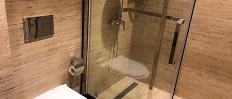 Un baño moderno con ducha de vidrio, inodoro y suelo de madera.