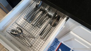 Un tiroir de cuisine contenant des ustensiles rangés de manière ordonnée dans un porte-ustensiles en fil métallique.