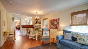 A cozy living room with a blue sofa, wooden dining table, and chairs. - Cute, Cozy Beach Cottage/Duplex - One block to the beach! Location is Key! (Isle of Palms)