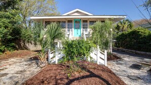 A house with a white exterior, a turquoise door, and a front porch. - Cute, Cozy Beach Cottage/Duplex - One block to the beach! Location is Key! (Isle of Palms)
