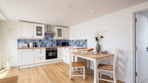 Une cuisine moderne avec des meubles blancs, un plan de travail en bois et un coin repas comprenant une table et des chaises.