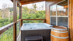 A wooden cabin with a hot tub, a wooden barrel, and a view of a forested landscape. -  Mt. LeConte Views! Cosy Luxury Cabin, Fire Pit, Hot Tub, Outdoor Pool, Location (Gatlinburg)