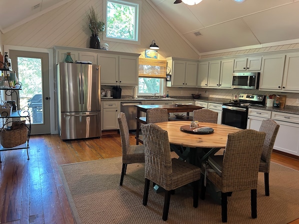 A kitchen with a dining table, chairs, and various appliances.