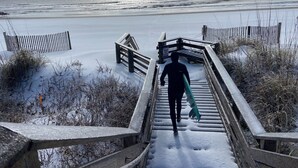 Un escalier en bois menant à une plage, avec un panneau indiquant «Ne pas marcher sur les dunes».