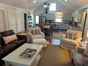 A spacious loft-style living area with a high ceiling, a dining table, and a kitchen in the background.