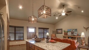 A spacious kitchen with granite countertops, a central island, and a ceiling fan.