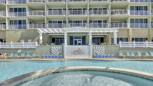 A hotel pool area with a clear view of the pool, lounge chairs, and a building with multiple balconies. - Luxury Beachfront Stay at Boardwalk – 2BR Condo w/ Balcony, Gulf Views & Free Perks (Panama City Beach)