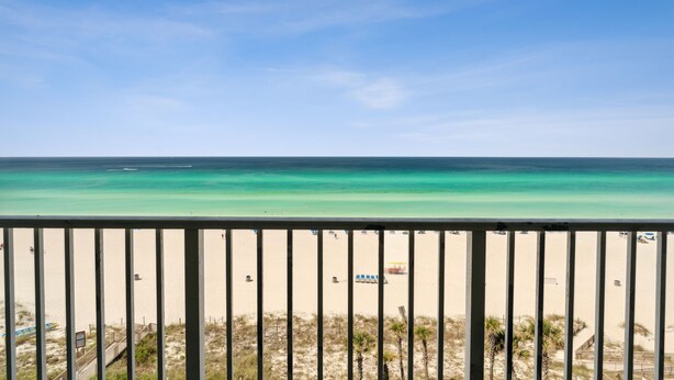 A beach view from a balcony with a railing, sandy beach, and clear turquoise water. - Luxury Beachfront Stay at Boardwalk – 2BR Condo w/ Balcony, Gulf Views & Free Perks (Panama City Beach)