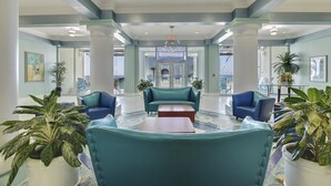 A lobby with teal sofas, a coffee table, and potted plants. - Luxury Beachfront Stay at Boardwalk – 2BR Condo w/ Balcony, Gulf Views & Free Perks (Panama City Beach)