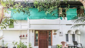 Un edificio blanco con un toldo verde, una puerta de madera y macetas con plantas.