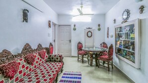 Una sala de estar con un sofá, sillas, una mesa de comedor y un aparador de vidrio.