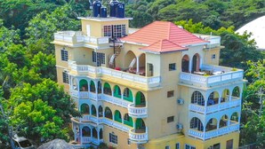 A multi-story hotel with a pool area, surrounded by lush greenery and hills. - Takuma Boutique Hotel Rooms & Suites Jamaica  (Montego Bay)