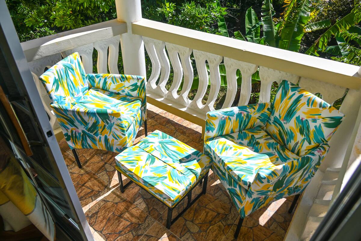 Ein Balkon mit zwei Stühlen und einem kleinen Tisch, umgeben von einem weißen Geländer.